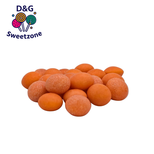 A pile of round orange candy-coated sweets on a light background, with the D&G Sweetzone logo in the top-left corner.